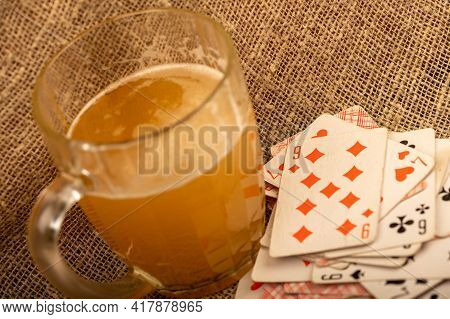 Playing Cards And A Glass Of Vodka On A Table Covered With Coarse Burlap. Close-up, Selective Focus.