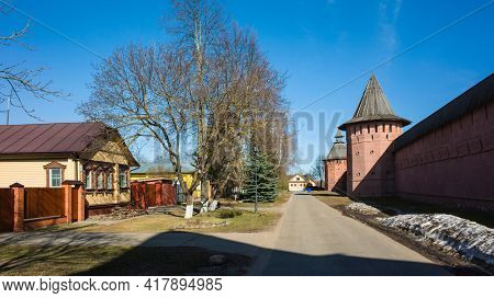 Street of Suzdal, Red Wall and towers of Saint Euthymius monastery, residential russian traditional house across road in sunny day in spring middle april, Golden Ring of Russia