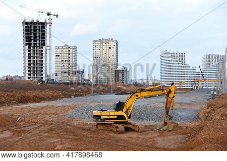 Excavator On Earthworks At Construction Site. Backhoe On Road Construction. Tower Cranes In Action O