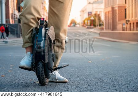 The Legs Of A Young Woman Ready To Ride An Electric Unicycle, Abbreviated Euc, Against The Backgroun