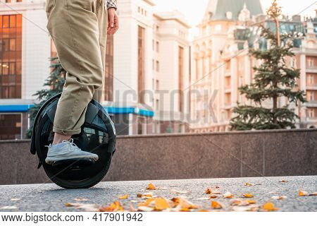 The Legs Of A Young Woman Ready To Ride An Electric Unicycle, Abbreviated Euc, Against The Backgroun