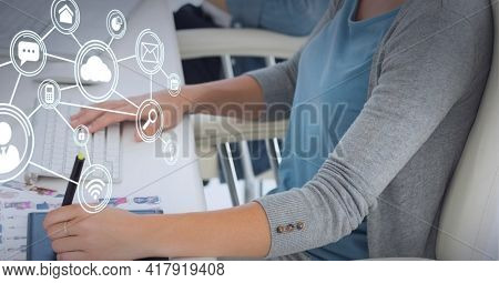 Composition of network of connections digital icons over woman using computer and graphic tablet. global technology and digital interface concept digitally generated image.