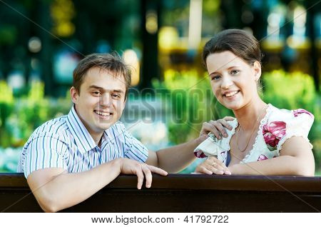 To smilende attraktive unge sidder på bænken i foråret park