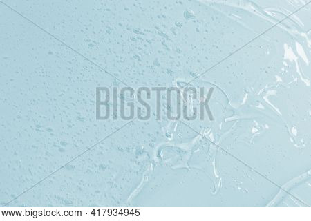 Abstract Cosmetic Background From Transparent Gel Or Antiseptic, Hyaluron On Blue Background