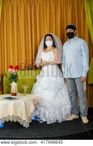 During The Chupa Ceremony In The Synagogue, The Masked Jewish Bride And Groom Stand Side By Side. Ve