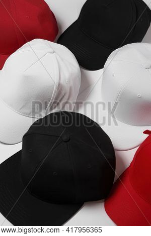 Closeup Of Set Of Baseball Snapback Hats In Different Colors Black, White And Red Laid Out Over Whit