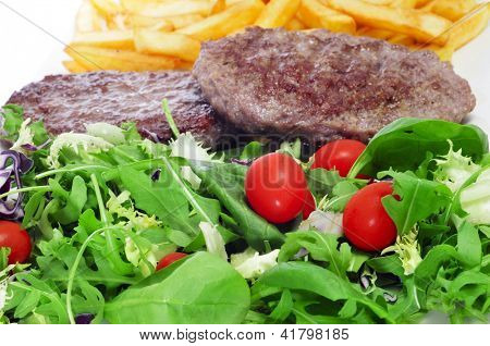Nærbillede af en combo fad med salat, burger og pommes frites