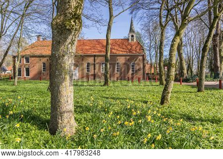 Narcissus Flowers In Front Of The Historic Church In Oudeschans, Netherlands