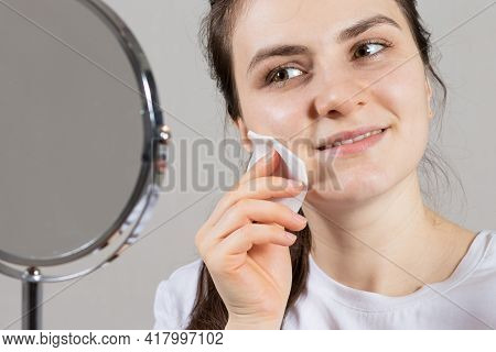 A 25-year-old Woman Holds A Face And Neck Tonic And A Cotton Pad. Anti-wrinkle Skin Care, Vitamins A