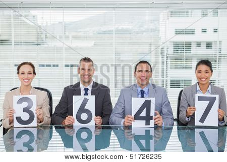 Smiling interview panel holding papers giving grade to their applicant in bright office