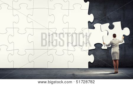 Immagine di imprenditrice che collega gli elementi del puzzle bianco