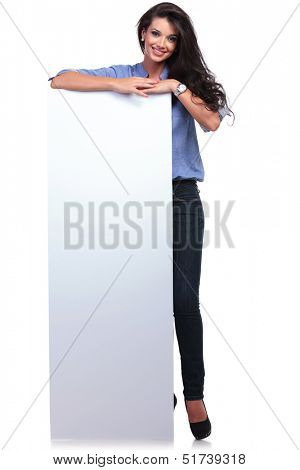 full length picture of a young casual woman with an empty pannel smiling for the camera. on white background