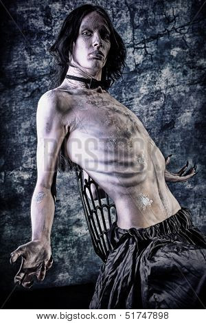Portrait of a scrawny vampire at the night cemetery. Halloween.