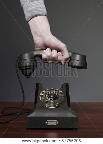 Man answering retro phone against a grey background