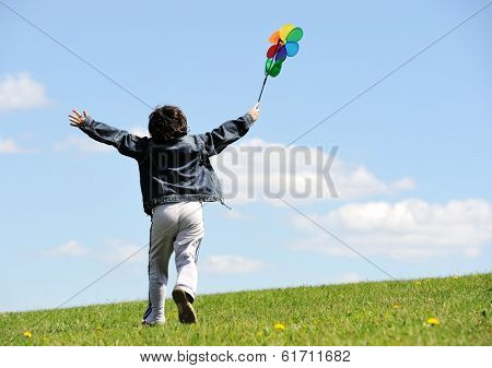 Cheerful kid having fun running on green summer meadow