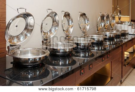 Table with shiny marmites in hotel restaurant
