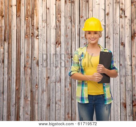 repair, construction and maintenance concept - smiling woman in helmet with clipboard
