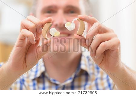 Man showing deaf aids in hands
