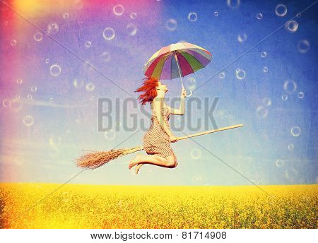 Red-haired Girl Fly With Umbrella Over Rape Field And Bubbles Around.