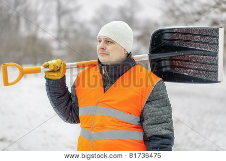 Worker with snow shovel in winter