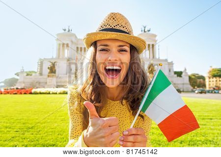 Portrait Of Happy Young Woman Showing Italian Flag And Thumbs Up On Piazza Venezia In Rome, Italy