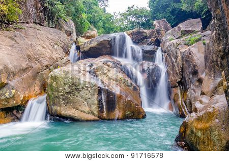 Jungle waterfall with flowing water, large rocks
