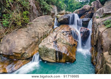 Jungle waterfall with flowing water, large rocks
