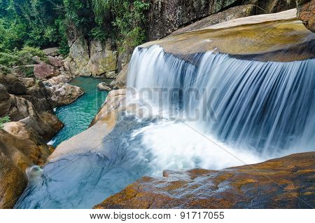Jungle waterfall with flowing water, large rocks