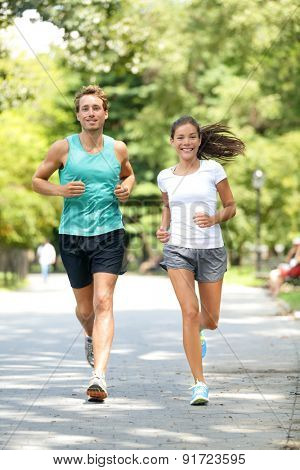 Fitness healthy lifestyle young couple training for marathon outside in Central Park, Manhattan, New York. Asian female model and Caucasian handsome sport fitness male. Happily enjoying jogging.