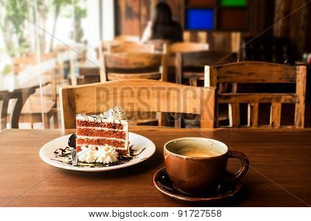Coffee cup with slice of cake on wood table in cafe