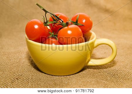 Red Cherry Tomatoes In A Yellow Cup On Old Cloth