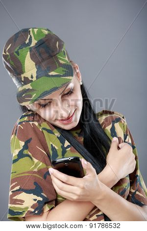 happy woman soldier looks at a mobile phone