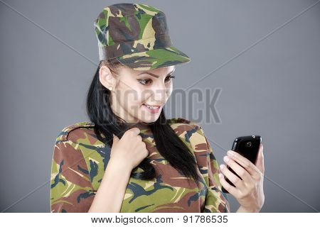 happy woman soldier looks at a mobile phone