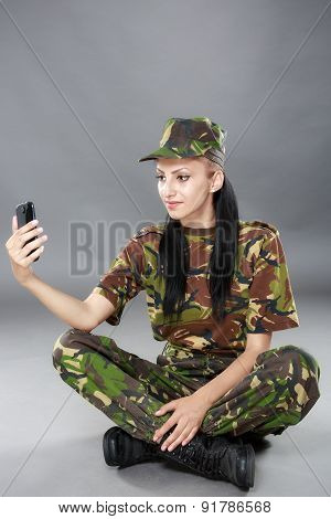 happy woman soldier looks at a mobile phone