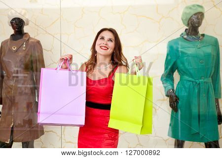 Half-length portrait of a beautiful girl with lots of packages surprised to see a big sell-mall near the dummies