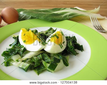 Eggs with fresh green chard vegetables on plate
