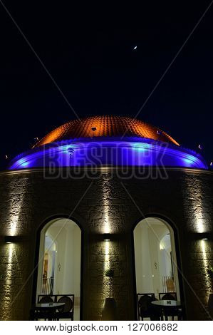 A dome with the moon in the evening with yellow color haughtiness and blue.