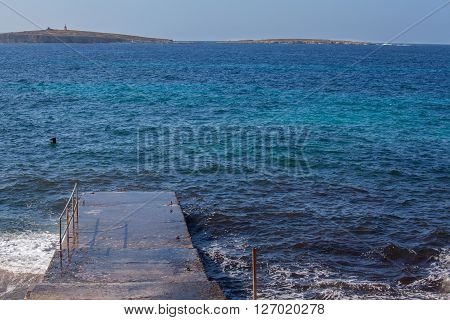 A cemented pier laying over a blue sea
