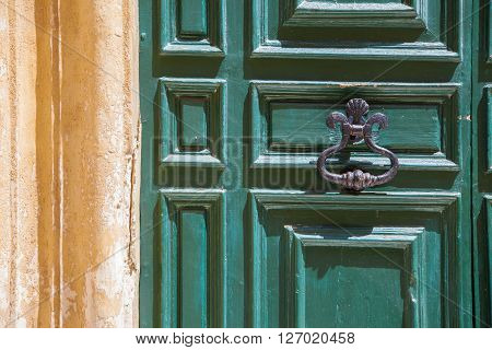 A wood green door with knob close to a yellow wall