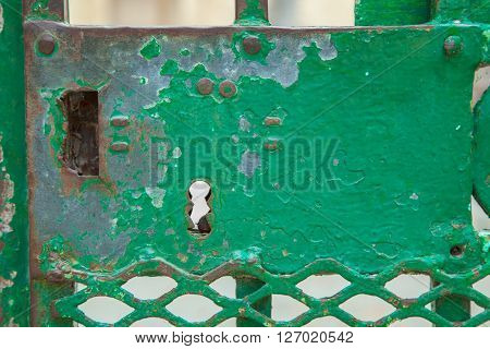 A green rusty lock on an iron door