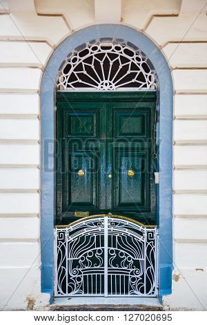 A geen wood door with white small fence and blue frame