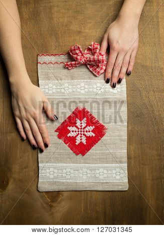Knitted handmade Gift Bag on wood background with woman hands