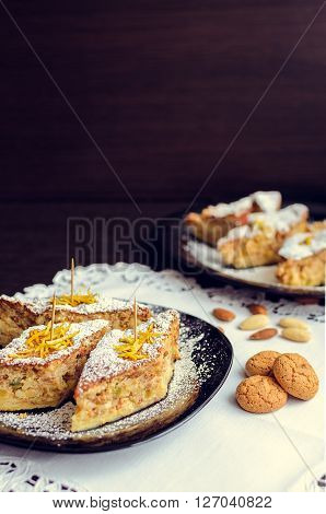Torta di riso - classical Italian dessert. Rice cake with almonds candied orange peels and amaretto. A slices of rice cake with almond cookies in a plate. Italian food. Selective focus.
** Note: Shallow depth of field