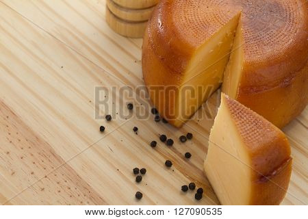 Cheese Wheel And Slice With Wooden Peppermill With Peppercorns