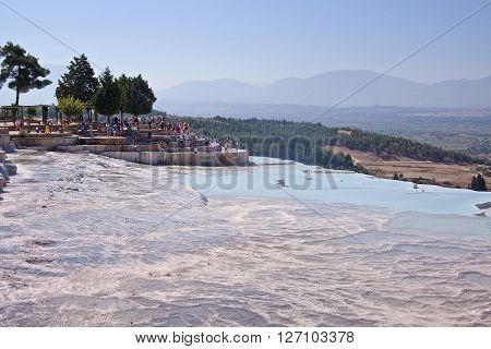 PAMUKKALE, TURKEY - September 13, 2015: Tourists regard the travertines with pools and terraces at Pamukkale. Pamukkale is included in the UNESCO World Heritage List.