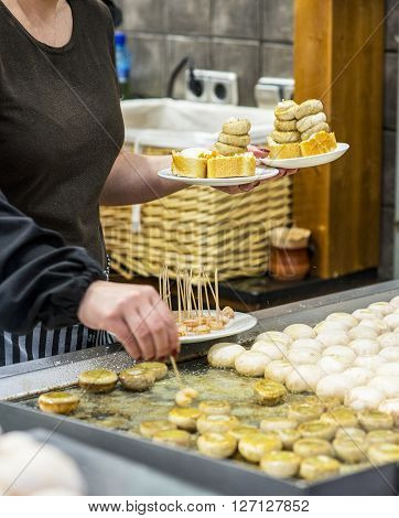 Cook cooking a typical spanish mushrooms pincho (Pintxo de champiñones) in a kitchen.