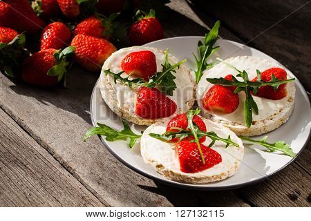 Multigrain rice cakes with strawberries fruit soft mascarpone cheese and arugula for healthy breakfast.