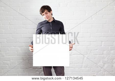 young man holding poster in brick room