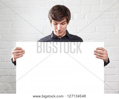 young man holding poster in brick room