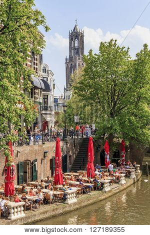 Utrecht, Netherlands - May 6: There are duplex embankments of the city with a cafe at the edge of the canal and the cathedral at a sunny day Domtoren May 6, 2013 in Utrecht, Netherlands.